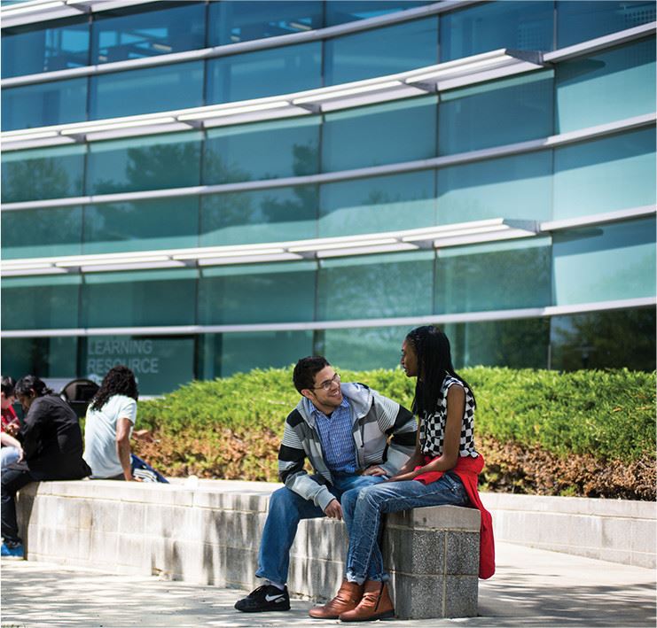 Two people sitting on a bench in front of a building